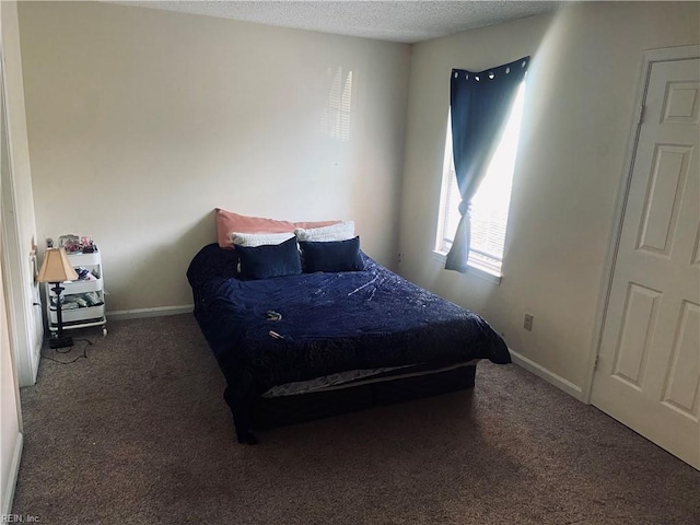 bedroom with dark colored carpet and a textured ceiling