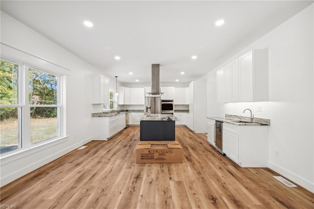 kitchen featuring white cabinets, light wood-type flooring, a center island, and extractor fan