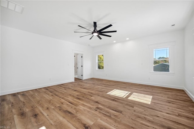 empty room with a wealth of natural light, ceiling fan, and wood-type flooring