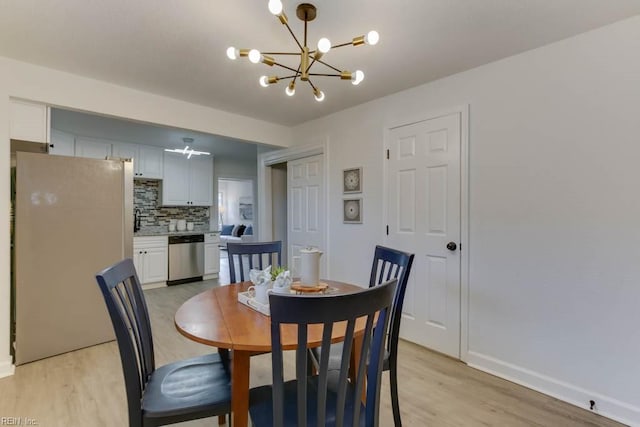 dining room with light hardwood / wood-style floors and a notable chandelier