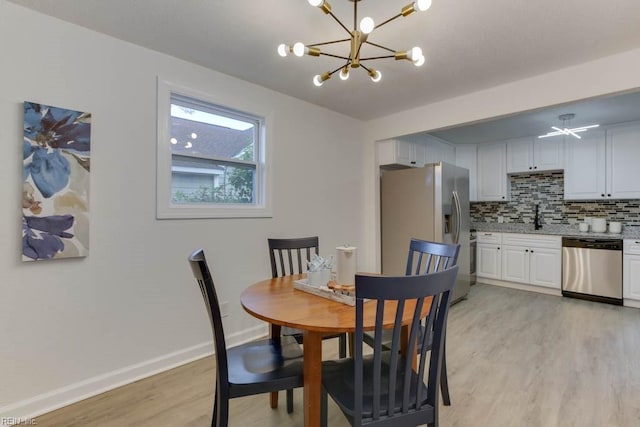 dining area with light wood-type flooring, a notable chandelier, and sink