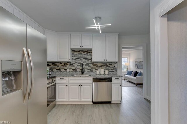 kitchen with white cabinets, sink, stainless steel appliances, and light hardwood / wood-style flooring