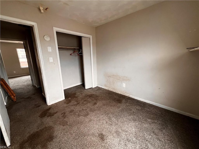 unfurnished bedroom featuring dark carpet and a closet