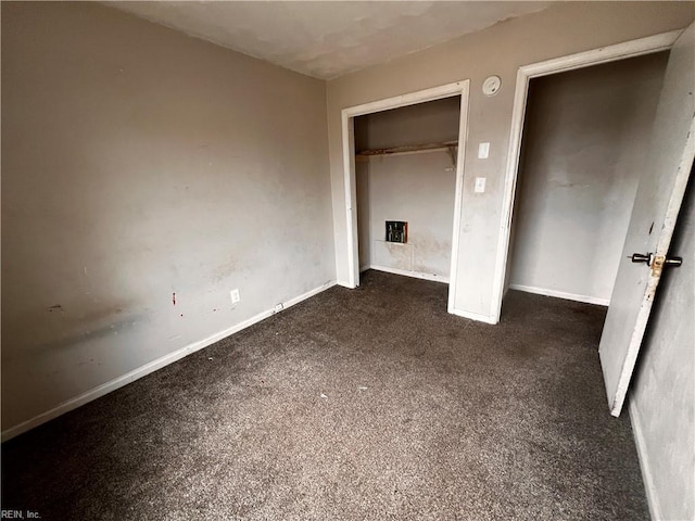 unfurnished bedroom featuring dark carpet and a closet