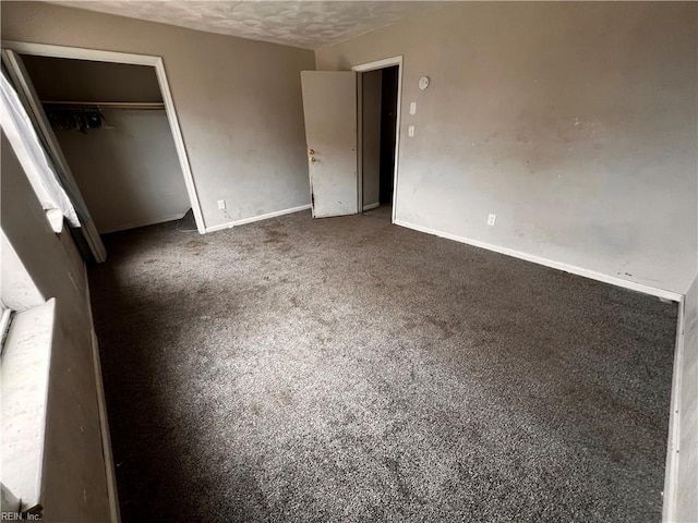 unfurnished bedroom featuring a closet, a textured ceiling, and dark colored carpet