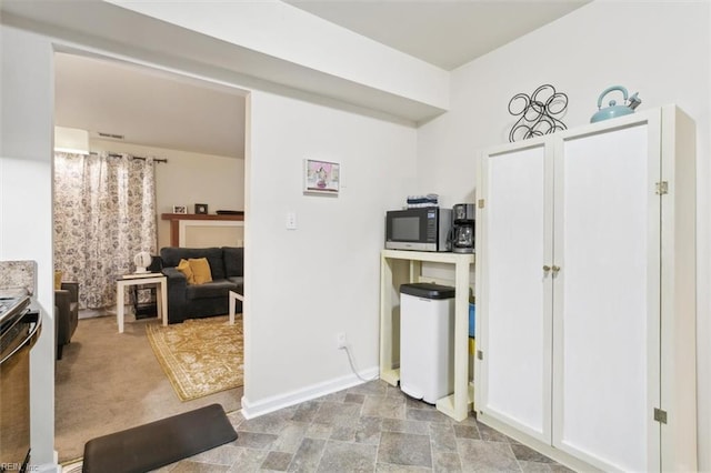 kitchen featuring white cabinetry, stainless steel appliances, and light carpet