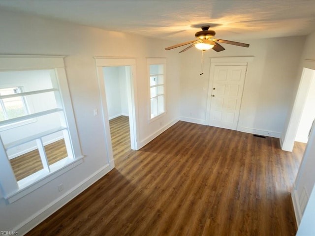 spare room featuring ceiling fan, plenty of natural light, and dark wood-type flooring