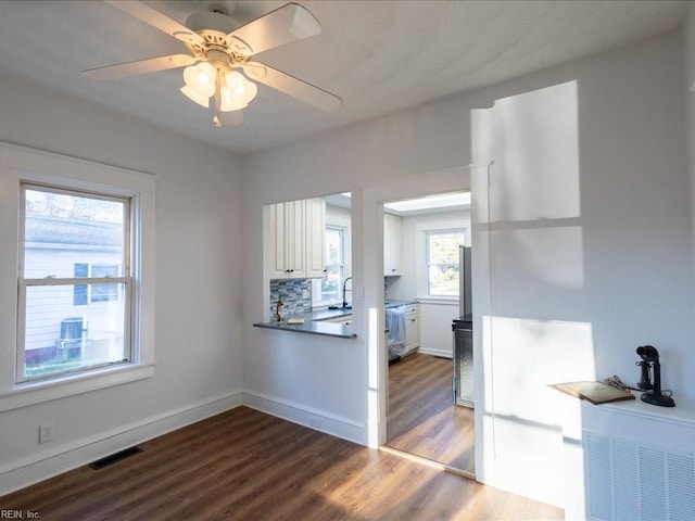 kitchen with decorative backsplash, ceiling fan, sink, wood-type flooring, and white cabinetry