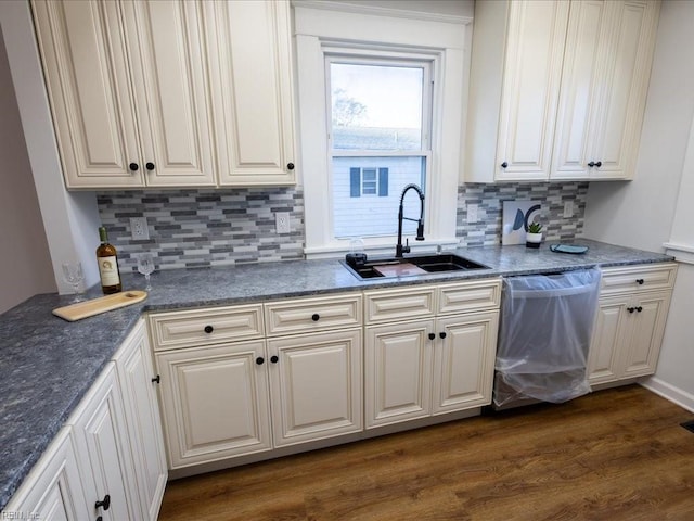 kitchen featuring tasteful backsplash, stainless steel dishwasher, dark wood-type flooring, and sink