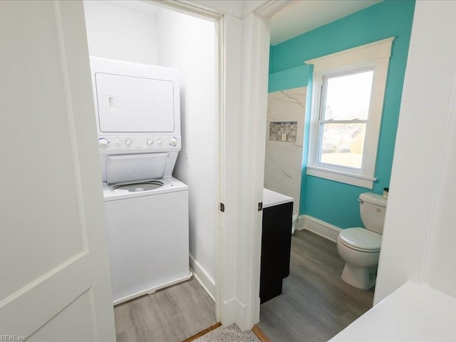 clothes washing area featuring stacked washing maching and dryer and hardwood / wood-style flooring