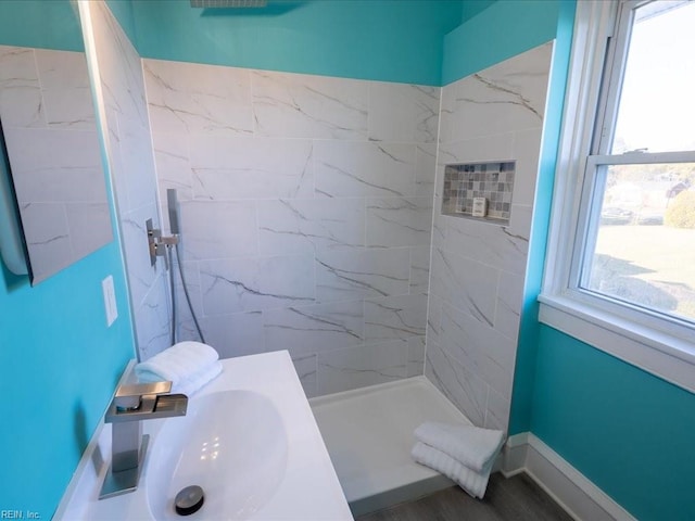 bathroom with a tile shower, sink, and wood-type flooring