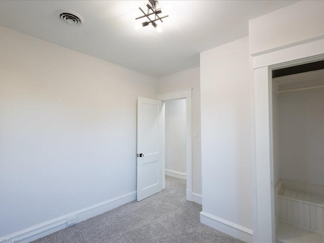 unfurnished bedroom with a closet and light colored carpet