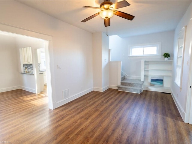 unfurnished living room featuring ceiling fan and dark hardwood / wood-style flooring