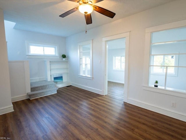 unfurnished living room featuring ceiling fan and dark wood-type flooring