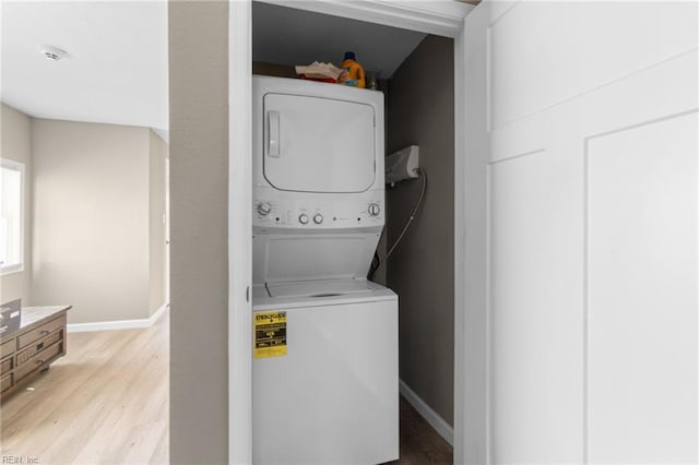 clothes washing area featuring stacked washing maching and dryer and light hardwood / wood-style flooring