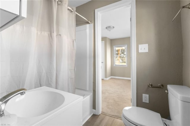 bathroom featuring shower / bathtub combination with curtain and toilet