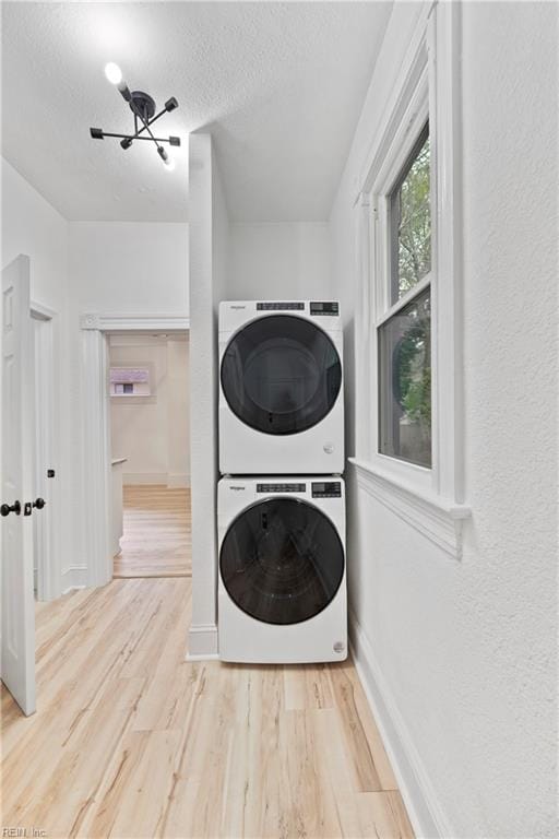 washroom with wood-type flooring, a textured ceiling, and stacked washer / drying machine