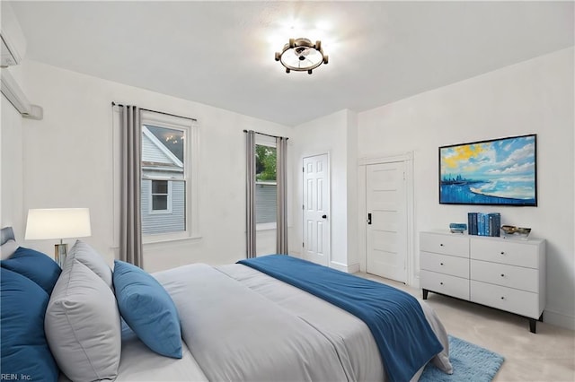 bedroom with a wall mounted air conditioner and light colored carpet