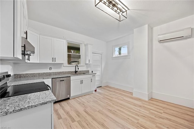 kitchen featuring black stove, dishwasher, sink, a wall mounted air conditioner, and white cabinets