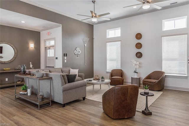 living room with crown molding, a towering ceiling, ceiling fan, and light hardwood / wood-style floors