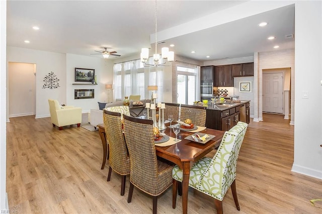 dining space with ceiling fan with notable chandelier, light hardwood / wood-style floors, and sink