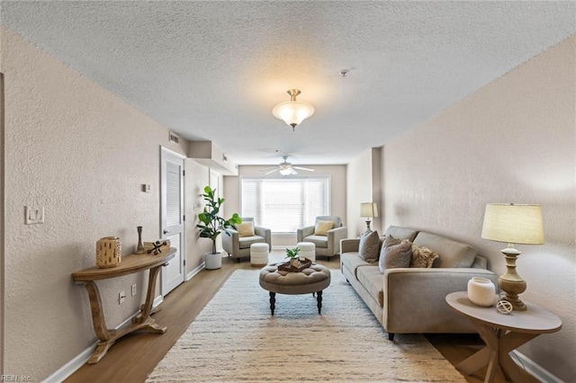 living room with ceiling fan, light hardwood / wood-style floors, and a textured ceiling