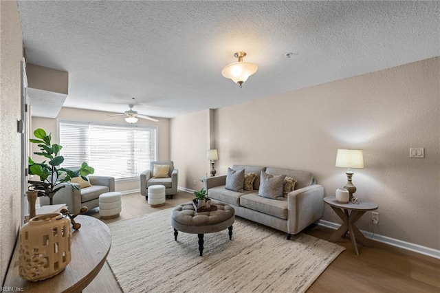 living room featuring wood-type flooring, a textured ceiling, and ceiling fan