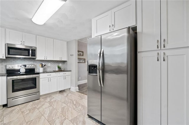 kitchen featuring tasteful backsplash, dark stone countertops, white cabinets, and stainless steel appliances