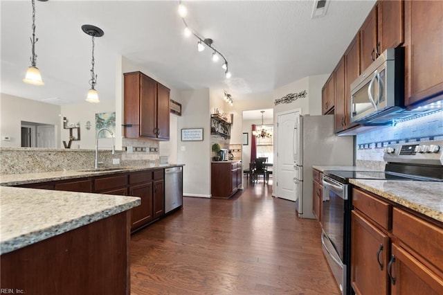 kitchen featuring appliances with stainless steel finishes, dark hardwood / wood-style flooring, backsplash, sink, and hanging light fixtures