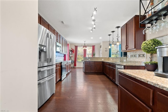 kitchen featuring sink, hanging light fixtures, dark hardwood / wood-style flooring, light stone counters, and stainless steel appliances