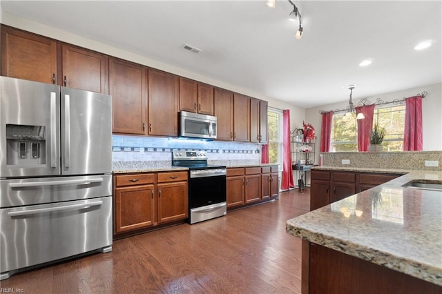 kitchen featuring appliances with stainless steel finishes, backsplash, decorative light fixtures, a notable chandelier, and dark hardwood / wood-style floors