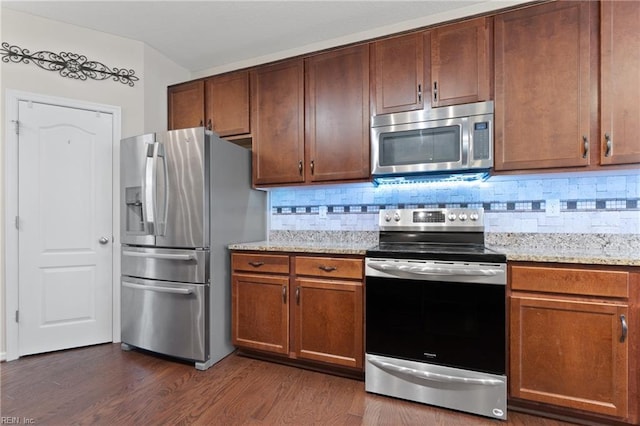 kitchen with light stone countertops, dark hardwood / wood-style floors, and appliances with stainless steel finishes