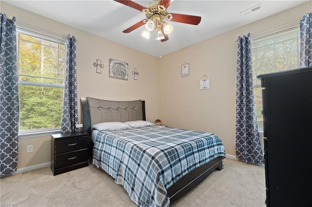 bedroom featuring ceiling fan, light colored carpet, and multiple windows