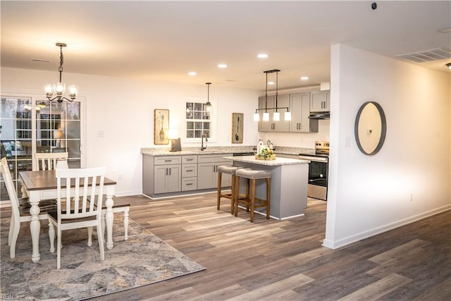 kitchen featuring stainless steel range with electric stovetop, gray cabinetry, pendant lighting, dark wood-type flooring, and a kitchen island