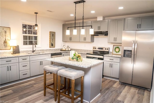 kitchen featuring a center island, sink, hanging light fixtures, appliances with stainless steel finishes, and dark hardwood / wood-style flooring