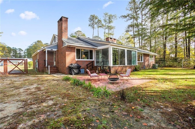 back of house featuring a yard, a patio, an outdoor fire pit, and a sunroom