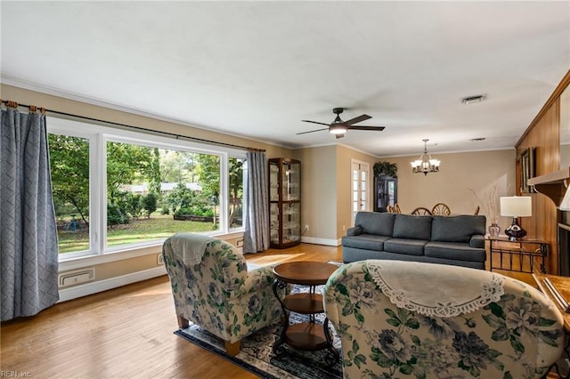 living room featuring ceiling fan with notable chandelier, light wood-type flooring, and crown molding