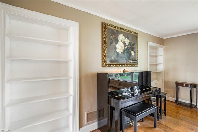 misc room with hardwood / wood-style flooring, built in features, and crown molding