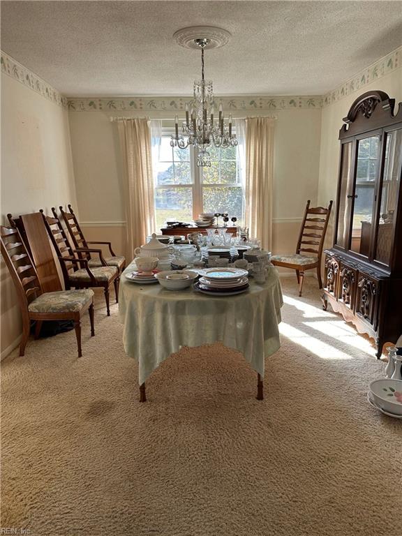 dining room featuring carpet, a textured ceiling, and a chandelier