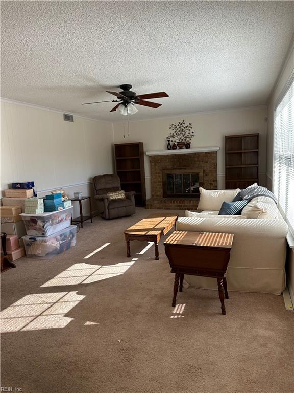 living room with carpet flooring, ceiling fan, a textured ceiling, and a brick fireplace