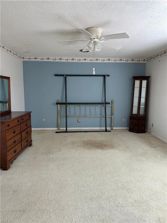 unfurnished bedroom with a textured ceiling, light colored carpet, and ceiling fan