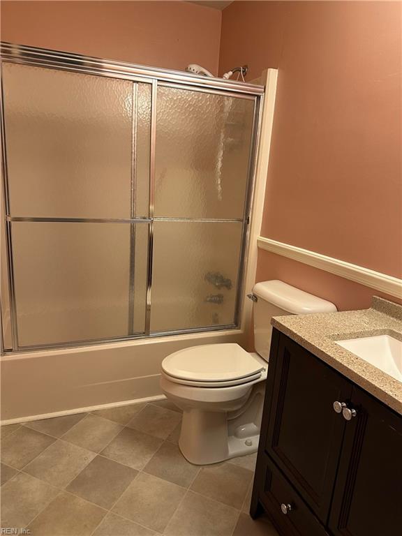 full bathroom with shower / bath combination with glass door, tile patterned floors, vanity, and toilet