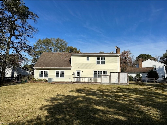 rear view of house featuring central AC unit, a wooden deck, and a lawn