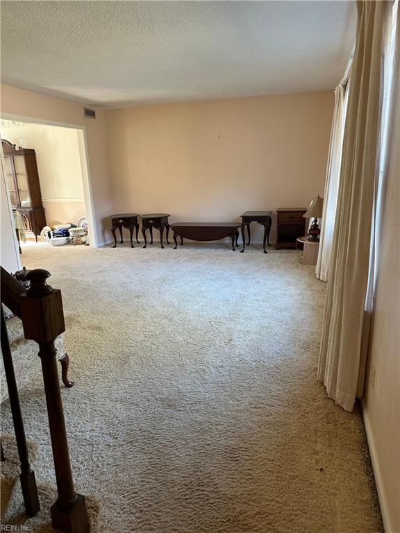 living area featuring light carpet and a textured ceiling