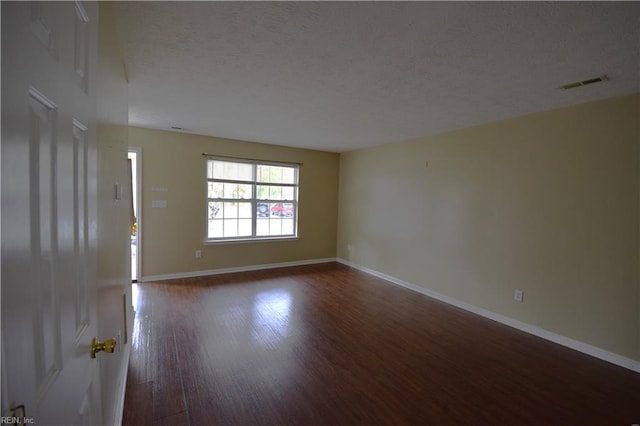 empty room with dark wood-type flooring and a textured ceiling