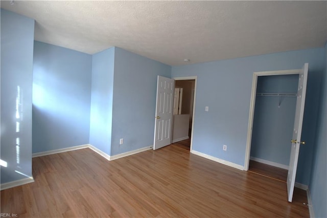 unfurnished bedroom featuring a closet, light hardwood / wood-style floors, and a textured ceiling