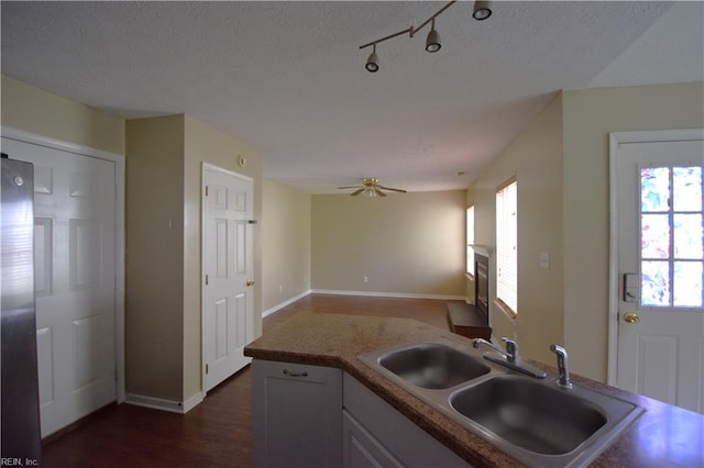 kitchen featuring stainless steel fridge, a textured ceiling, ceiling fan, dark wood-type flooring, and sink