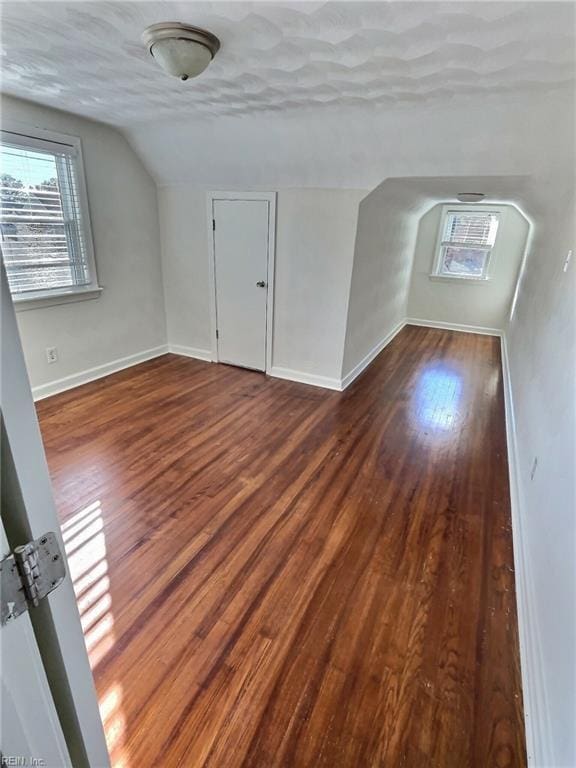 bonus room featuring a textured ceiling, dark wood-type flooring, and lofted ceiling