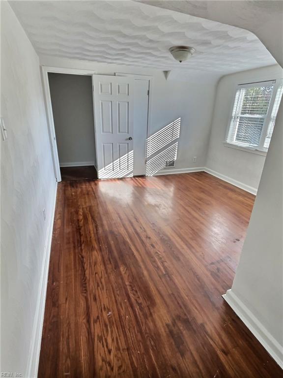 interior space with a textured ceiling and dark hardwood / wood-style flooring