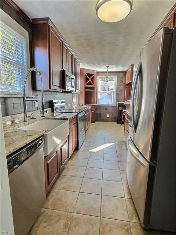 kitchen with stainless steel appliances, sink, pendant lighting, light tile patterned floors, and a notable chandelier